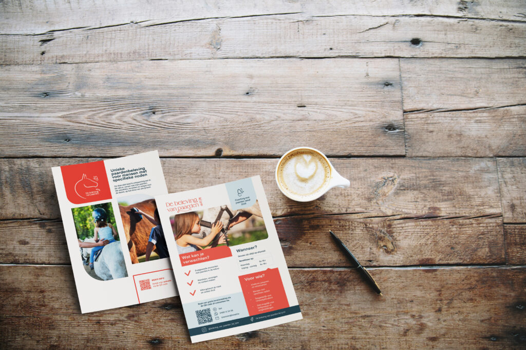 Twee flyers van De beleving van paarden bij Lynn op een houten tafel, naast een kopje koffie en een pen.